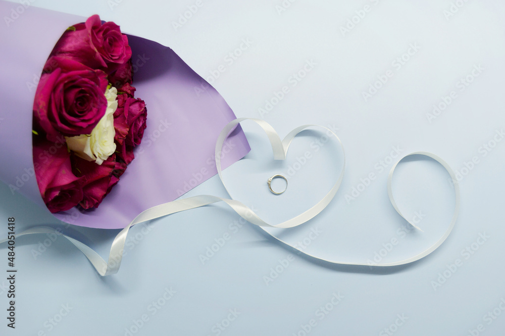 Bouquet of red roses in purple packaging lies on a blue background Bouquet of red roses in purple packaging lies on a blue background