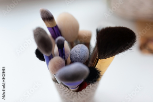 Makeup brushes, different sizes, in a glass.