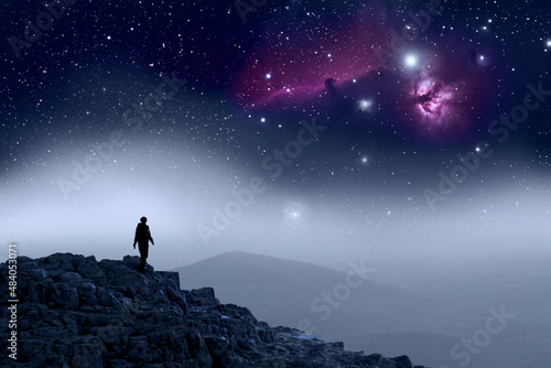 Photographie Human Silhouette walking on top of mountain, galaxy sky
