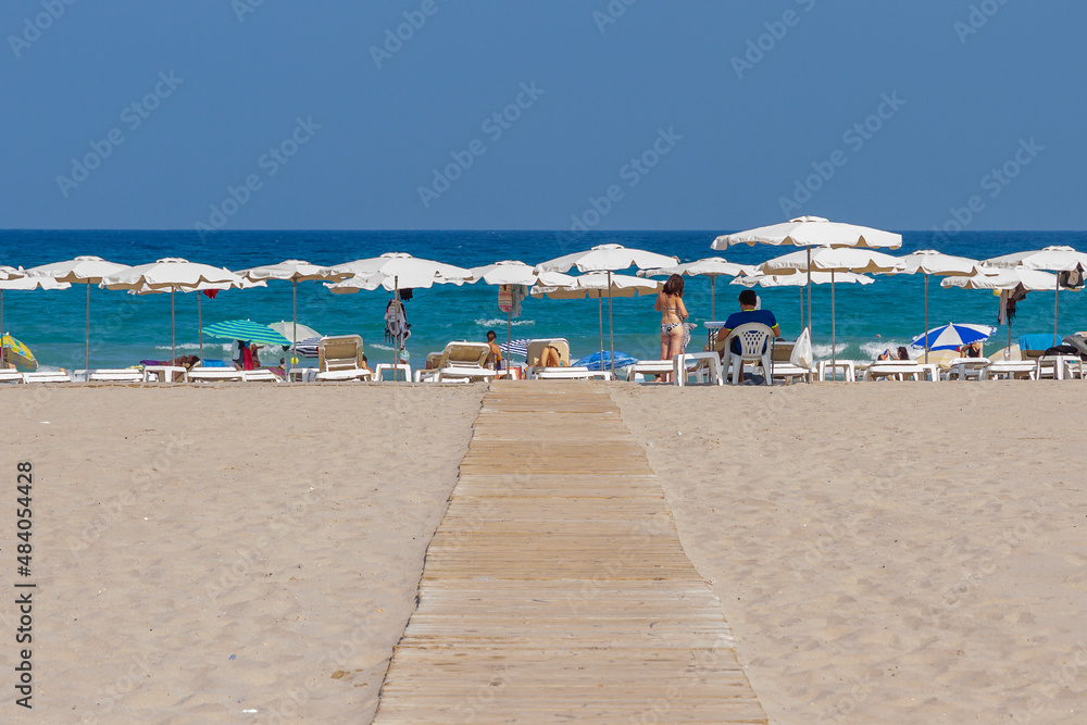 beach shore with sunbathers under white umbrellas