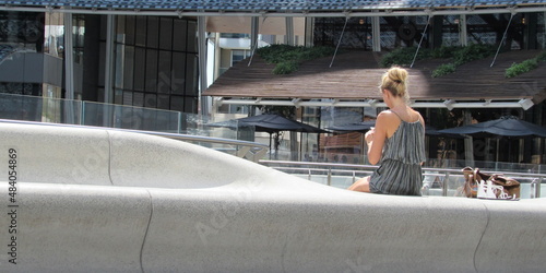 Giovane ragazza bionda seduta su un muretto in piazza - relax photo