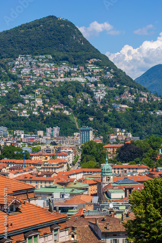 View of Old Town Lugano, Switzerland. The scenic cityscape and red rooftops of Lugano -- Cathedral of Saint Lawrence bell tower in the foreground