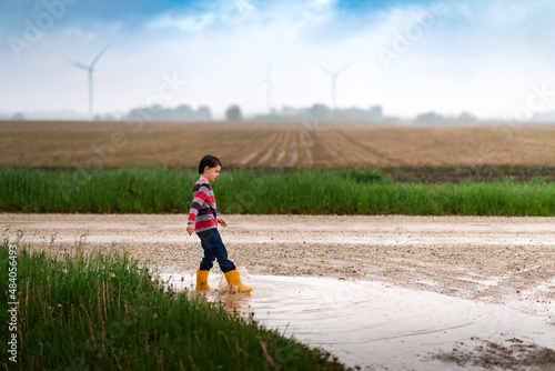 a boy playing in a puddle outside after a rain shower photo