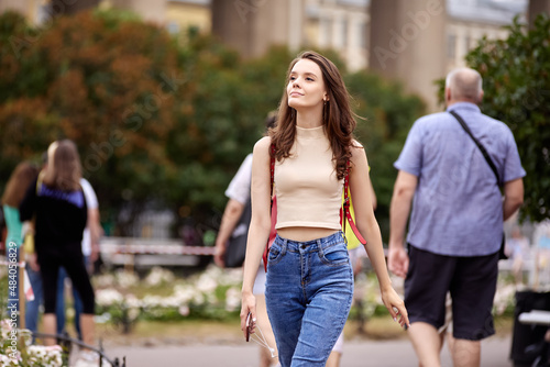 Slim woman in jeans walks in park in St. Petersburg.