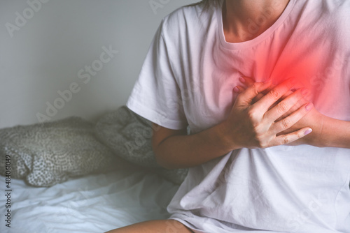Woman holding chest because of acute heart pain or chest pain. Heart disease and heart attack symptom