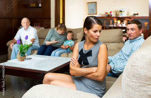 Young frustrated woman sitting separately having problems in relationship with her large family