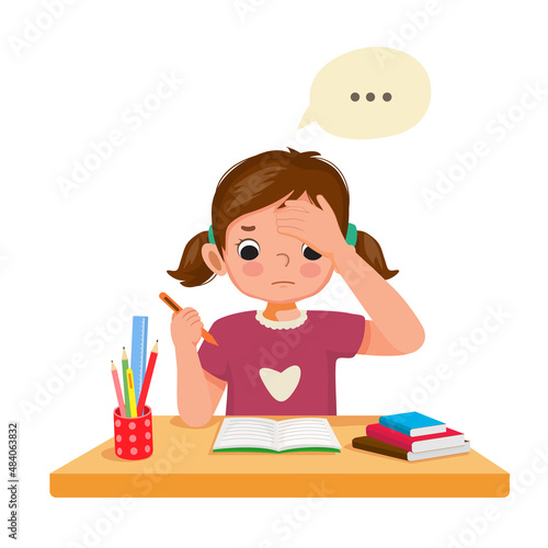 Little girl feeling tired, bored and lazy studying, doing her homework at the desk at home