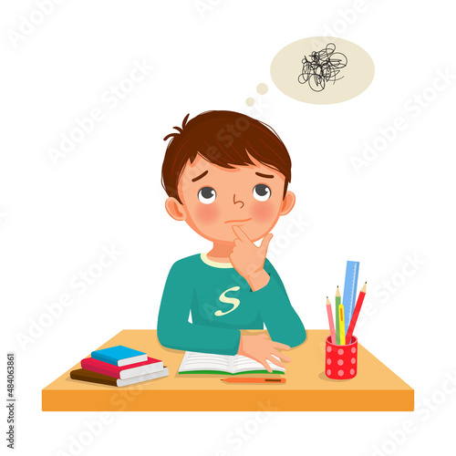 little boy thinking while studying and doing his homework at the desk
