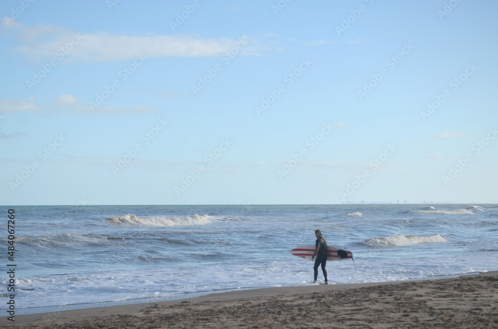 Surfista entrando al mar a la tarde