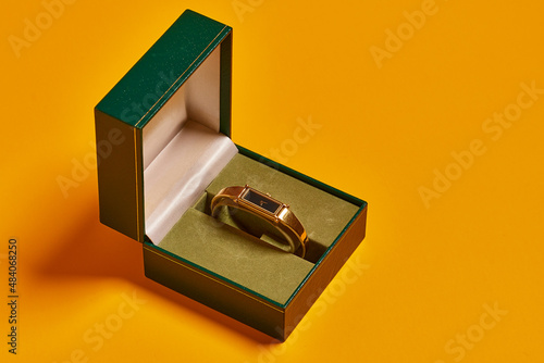 Luxury jewelry on yellow background. gold watch with green house. Product photography.