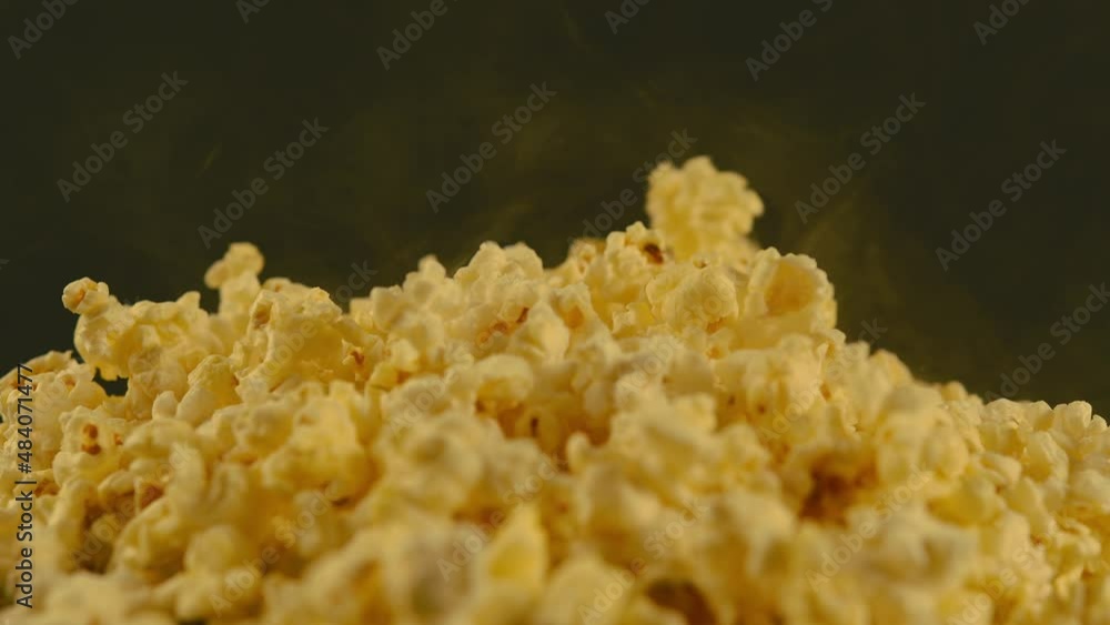 Pile of appetizing popcorn with dissipating steam. Unrecognizable person throws freshly cooked hot popcorn. Close up. Concept of snack for movie. Pile of appetizing popcorn with dissipating steam. Unrecognizable person throws freshly cooked hot popcorn. Close up. Concept of snack for movie.