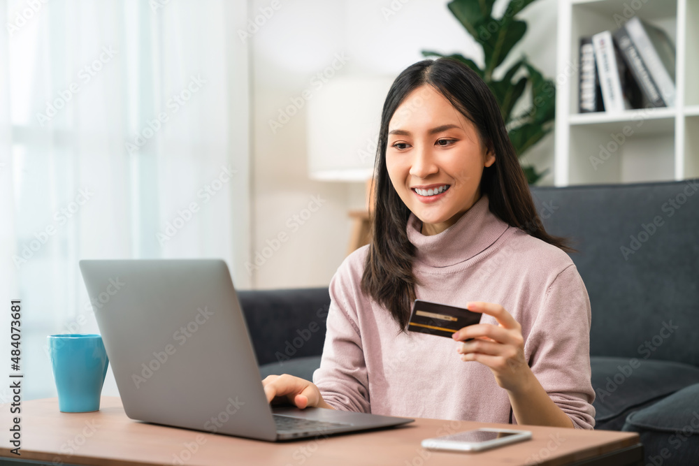 Young Asian woman holding credit card and using laptop for shopping online with payment on internet banking. Young Asian woman holding credit card and using laptop for shopping online with payment on internet banking.