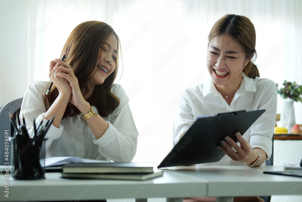 Two cheerful business women working together at modern office. Two cheerful business women working together at modern office.