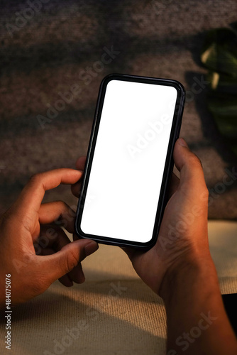Close up view man holding mockup mobile phone with empty screen for advertisement text. © wattana