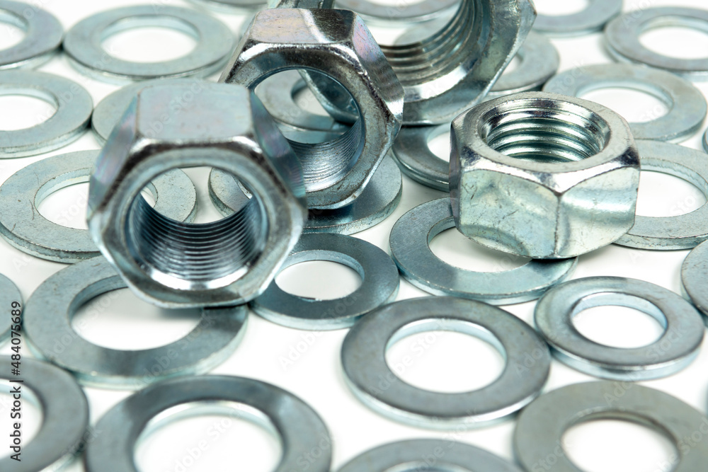 several metal washers and large nuts of silver color on a white background. close-up several metal washers and large nuts of silver color on a white background. close-up