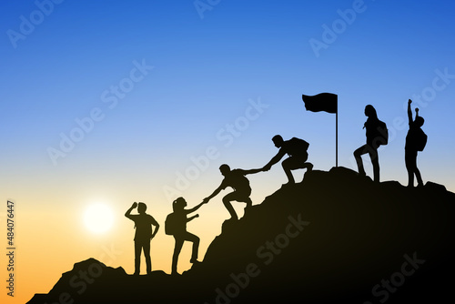 Silhouette of people helping each other hike up a mountain at sunrise. Business, teamwork, goal, success and help concept.