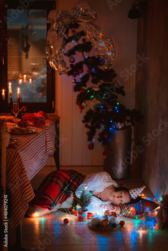 Peacefully sleeping woman covered with blanket under Christmas tree resting after New Year party