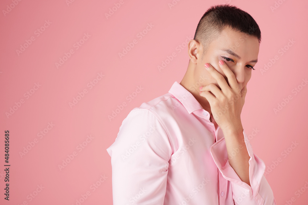Portrait of sad pensive young man with makeup covering mouth and looking down Portrait of sad pensive young man with makeup covering mouth and looking down