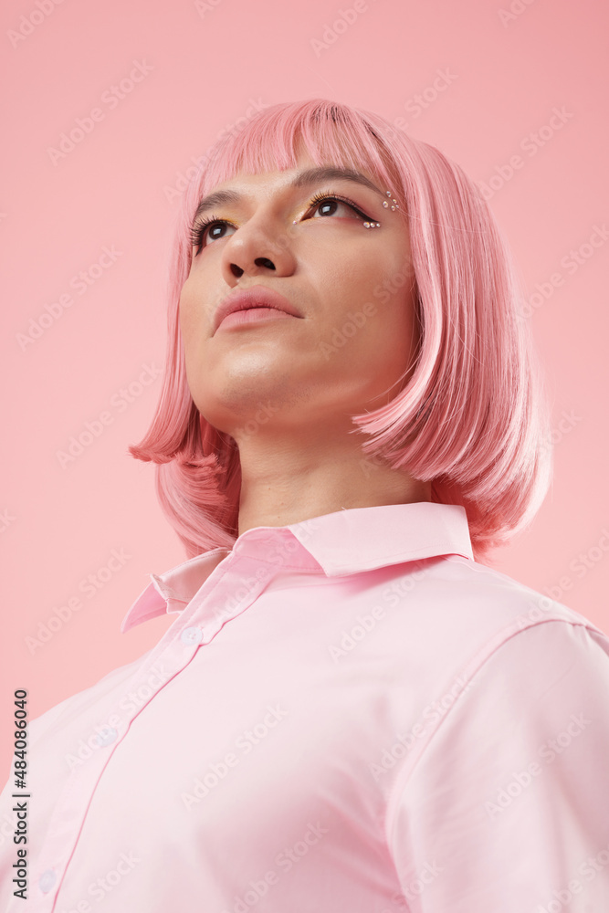 Confident young man wearing pink wig and bright make-up with sparkling rhinestones Confident young man wearing pink wig and bright make-up with sparkling rhinestones