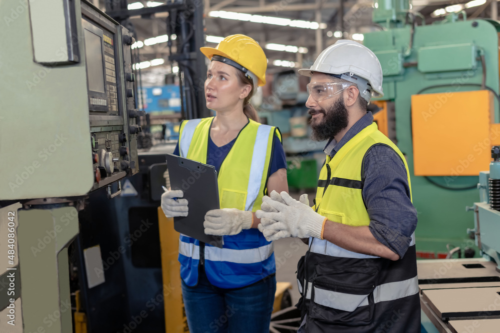 Two factory workers on safety uniform, hard helmet and vast working in industrial factory Two factory workers on safety uniform, hard helmet and vast working in industrial factory