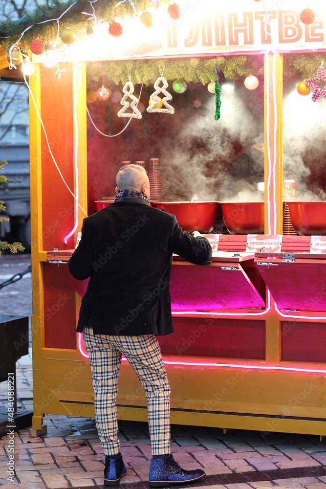 Man ordering mulled wine at kiosk at the Christmas market