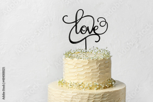 Obraz na plátně Beautiful wedding cake and topper with word LOVE on light background