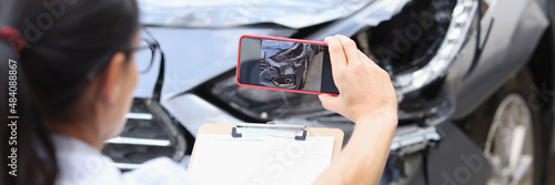Insurance agent takes pictures of damage to car after accident on smartphone