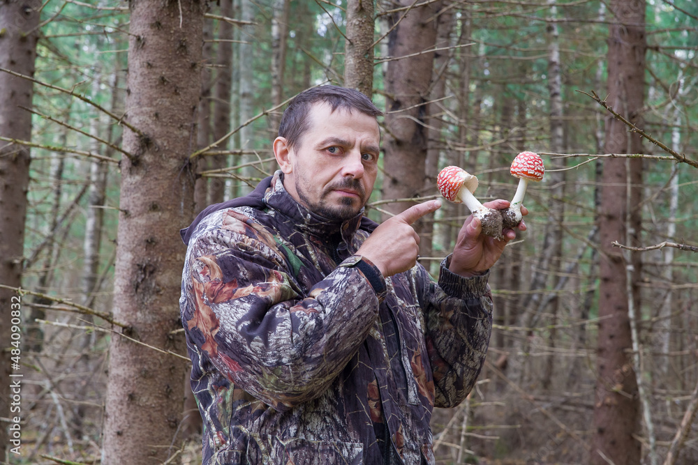 Funny man - a European holds two fly agaric mushrooms in his hands.