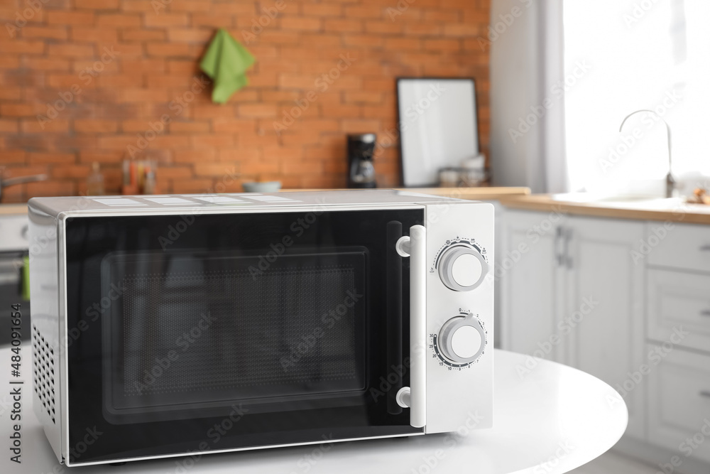 Microwave oven on white table in stylish kitchen Microwave oven on white table in stylish kitchen