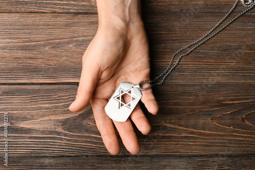 Εκτύπωση καμβά Hand with military tag of Israeli soldier on wooden background