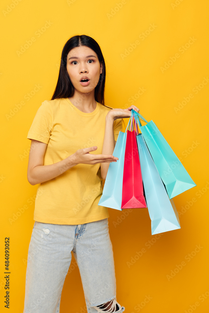 pretty brunette in a yellow T-shirt with multicolored shopping bags studio model unaltered pretty brunette in a yellow T-shirt with multicolored shopping bags studio model unaltered