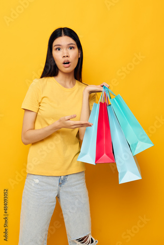 pretty brunette in a yellow T-shirt with multicolored shopping bags studio model unaltered