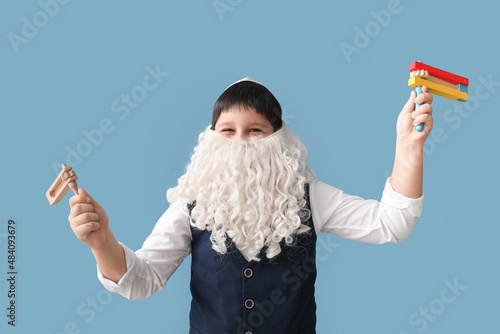 Funny Jewish boy with graggers for Purim holiday and fake beard on grey background photo