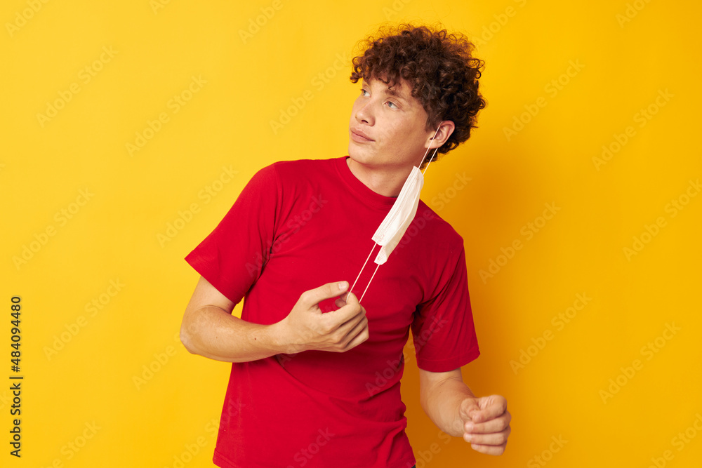 Young curly-haired man in a red t-shirt medical mask protection Lifestyle unaltered Young curly-haired man in a red t-shirt medical mask protection Lifestyle unaltered