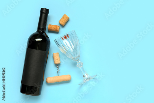 Bottle of wine, corks, glass and opener on blue background