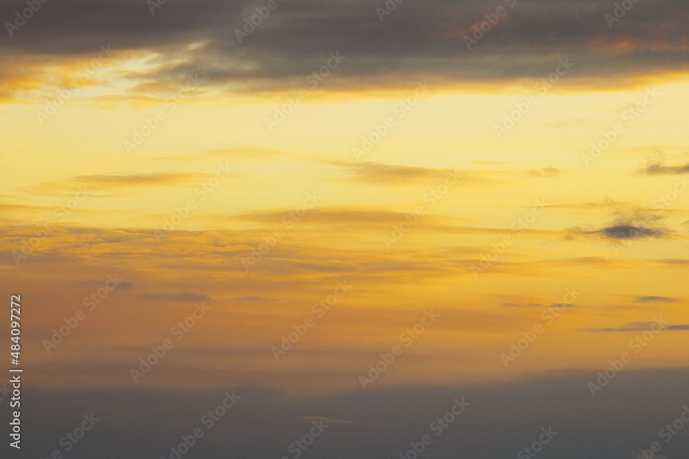 Sun below the horizon and clouds in the fiery dramatic orange sky at sunset or dawn backlit by the sun. Place for text and design, wallpaper and background