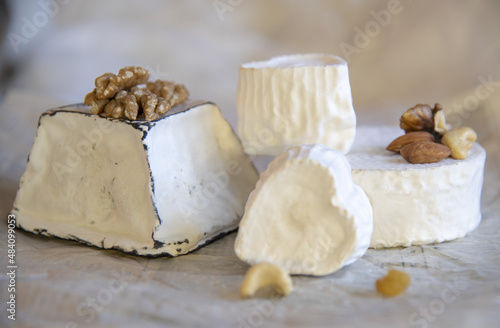 Various types of cheese with white mold on packaging paper.