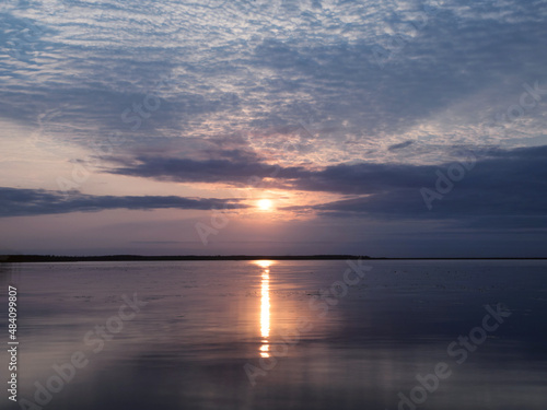 View of clouds reflected in the smooth water of the lake at sunset.