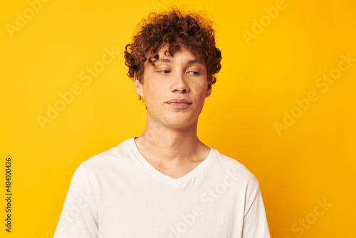 curly red-haired guy in a white t-shirt on a yellow background © Tatiana