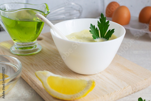 Homemade mayonnaise in a white bowl with parsley leaf and olive oil. The concept homemade food. Horizontal orientation.