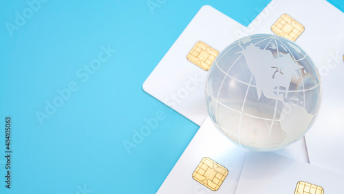 Buy now pay later  BNPL consumerism and global credit concept with transparent glass globe on credit cards isolated on blue background and copy space