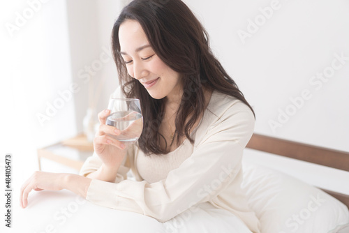 寝室のベッドで水を飲む女性