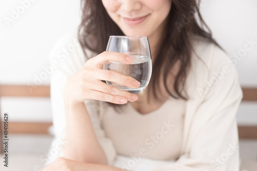 ベッドで水を飲む女性