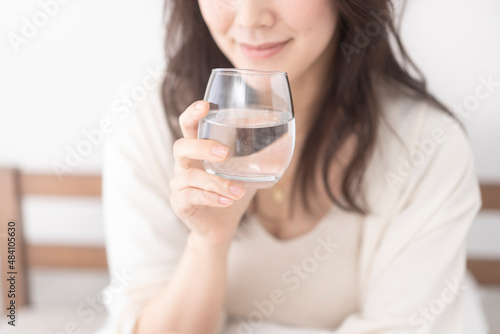 ベッドで水を飲む女性