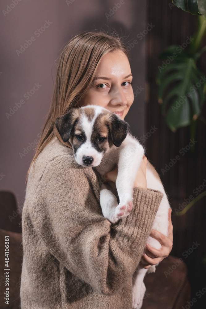 The girl holds a small white mongrel puppy in her arms and hugs him