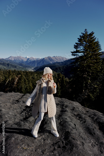 woman in autumn clothes stands on a rock blue sky lifestyle