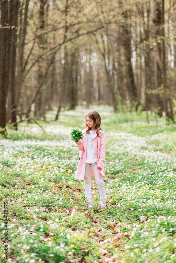 Baby girl with a bouquet of primroses in the spring forest Baby girl with a bouquet of primroses in the spring forest