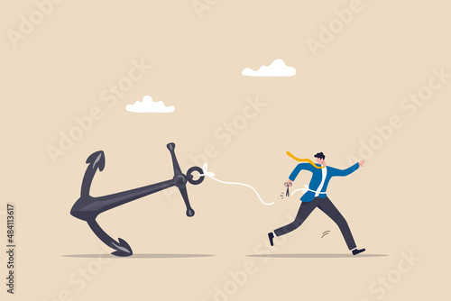 Freedom, relief or escape from bad habit, psychology anchoring effect or cut heavy burden to growing more concept, businessman using scissor to cut the rope tie himself with big heavy anchor. photo