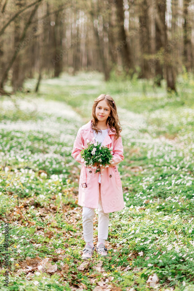 cute girl with a bouquet of primroses in the spring forest. A child on a walk in the park cute girl with a bouquet of primroses in the spring forest. A child on a walk in the park