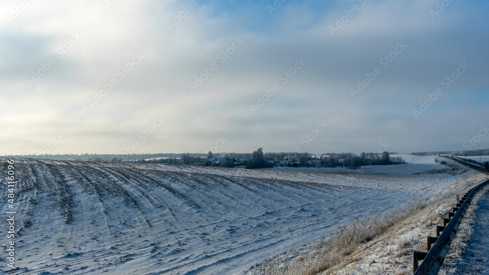 Winter farmland scenery landscape under snow with trees on background. Winter landscape with snow covered countryside.